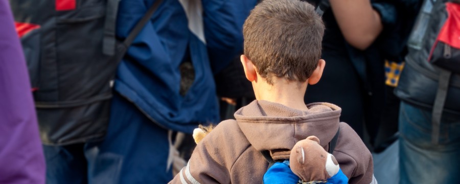 Flüchtlingskind mit Rucksack und Stofftier