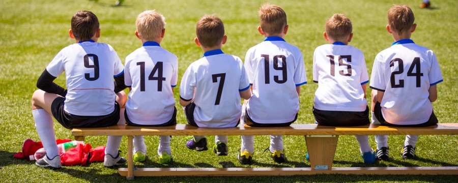 Kinder auf Bank am Sportplatz